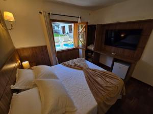 a bedroom with a bed and a window and a television at The Winter Mountain Hotel in Monte Verde