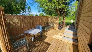 a patio with two chairs and a table on a wooden deck at le verger des Sy Pommier in Picauville