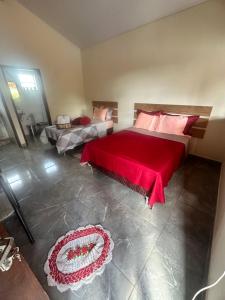 a bedroom with a large bed with a red blanket at Chalé do coiote 2 in São Roque de Minas
