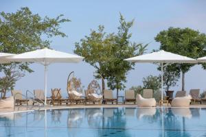 a swimming pool with chairs and umbrellas at Elma Hotel and Art Complex in Zikhron Ya'akov