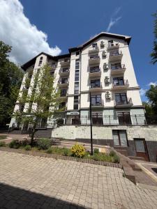 a tall white building with a sidewalk in front of it at Карпати Кайзервальд апарт in Karpaty