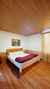 a large bed in a bedroom with a wooden floor at Nathia Lodge Cottage in Nathia Gali