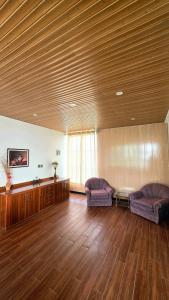 a living room with two chairs and a wooden ceiling at Nathia Lodge Cottage in Nathia Gali