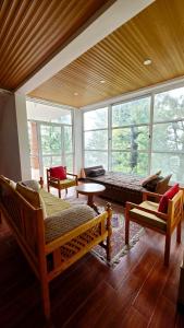 a room with a bed and a couch and windows at Nathia Lodge Cottage in Nathia Gali