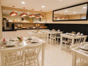 a dining room with white tables and white chairs at Pousada Jasmim in Gramado