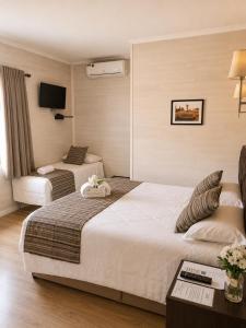 a hotel room with two beds and a television at Pousada Jasmim in Gramado