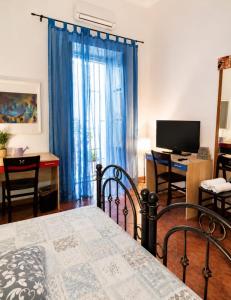 a bedroom with a bed with blue curtains and a desk at Guglielmo room's B&B in Catania