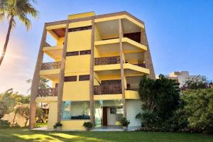 a yellow building with palm trees in front of it at Pousada Sunrise Beach in Cumbuco