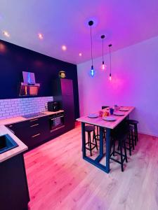 a kitchen with a table with chairs and purple lights at Quartier Général des Gamers Arcade Terrasse in Saint-Omer
