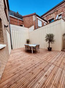 a patio with a table and chairs on a wooden deck at Quartier Général des Gamers Arcade Terrasse in Saint-Omer