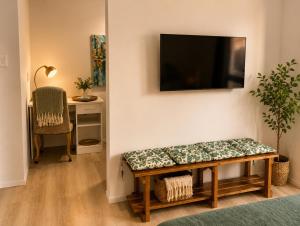 ein Wohnzimmer mit einer Bank und einem Fernseher an der Wand in der Unterkunft Flip-Flops studio in Hermanus