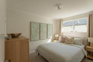 a white bedroom with a bed and a window at The Sun Deck Five Star Focused Downtown Location in Mount Maunganui