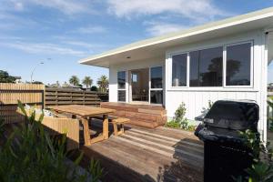 a house with a wooden deck with a picnic table at The Sun Deck Five Star Focused Downtown Location in Mount Maunganui +19 photos