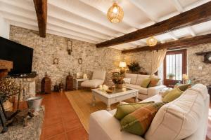 a living room with white furniture and a stone wall at Casa La Portilla in Labarces