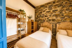 two beds in a room with a stone wall at Casa La Portilla in Labarces