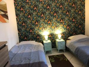 Zwei Einzelbetten in einem Zimmer mit Blumentapete in der Unterkunft APPARTEMENT 3 LITS Parking Proche Rouen Dock in Canteleu