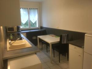 eine kleine Küche mit Spüle und Tisch in der Unterkunft APPARTEMENT 3 LITS Parking Proche Rouen Dock in Canteleu
