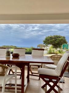 a wooden table and chairs on a patio with a view at Sweet Home Spalmatore in Carloforte