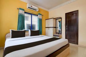 a bedroom with a large bed with green curtains at Hotel O Shyam sundar Hotel in kolkata