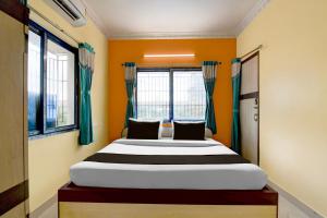 a bed in a room with orange walls and windows at Hotel O Shyam sundar Hotel in kolkata
