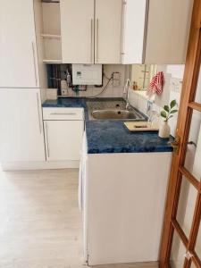 a kitchen with white cabinets and a sink at Stylish Studio with SuperKing Bed in Stonewood +4 photos