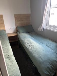 zwei Betten in einem kleinen Zimmer mit Fenster in der Unterkunft Ash 19 in Newton