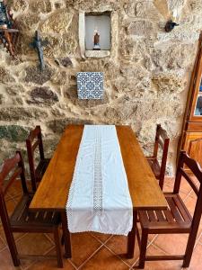 a wooden table with two chairs and a stone wall at Casa D Dinis in Alfaiates