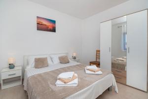 a white bedroom with a bed with towels on it at Apartments Saric in Jadrtovac