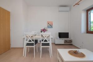 a white dining room with a white table and chairs at Apartments Saric in Jadrtovac