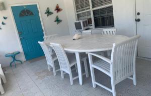 a white table with chairs and a cat sitting on top at SUITE 1, BLUE PAVILION - Steps to BEACH - NEW AC in West Bay