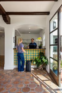 a man and a woman with a suitcase in a lobby at La Playa Inn Santa Barbara in Santa Barbara