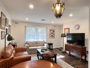a living room with a couch and a television at Cozy Lovely flat 3km to CBD in Glenunga