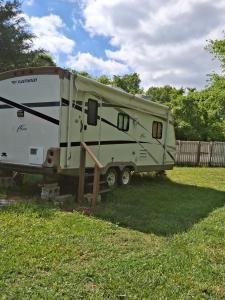a camper parked in a field next to a fence at Private Cozy Camper in Burnside