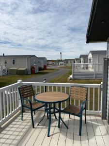 a table and two chairs sitting on a deck at Dune View Caravan in Lossiemouth