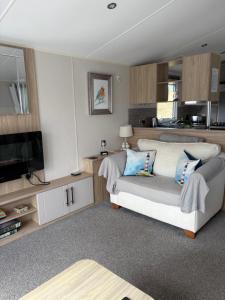 a living room with a couch and a television at Dune View Caravan in Lossiemouth