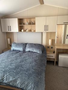 a bedroom with a bed and white cabinets at Dune View Caravan in Lossiemouth
