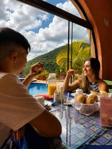 a man and a woman sitting at a table eating food at Pousada Santa Fe de Penedo in Penedo