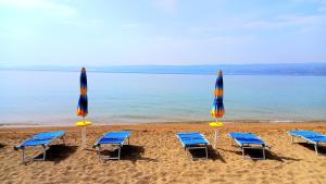four beach chairs and umbrellas on a beach at Bugenvilija in Duće