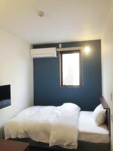 ein Schlafzimmer mit einem weißen Bett und einem Fenster in der Unterkunft からつホテルQueendom in Karatsu