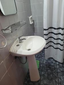 a white sink in a bathroom with a shower curtain at La Casa de Teresa in Colonia del Sacramento