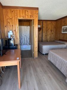 a room with two beds and a desk and a table at Glacier View Inn in Haines Junction