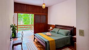 a bedroom with a bed and a table and a window at Casa Smile in Teresópolis