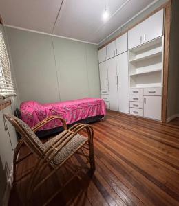 a room with a pink bed and a chair in it at Barrio Parque Residence in Caleta Olivia