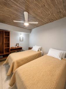 a bedroom with two beds and a ceiling fan at Hotel Belgrano in Tilcara
