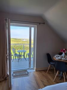 a room with a door open to a balcony with a table and chairs at Moher Heights in Liscannor