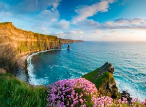 a person swimming in the ocean next to a cliff at Moher Heights in Liscannor