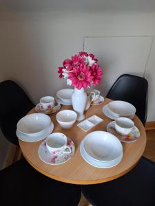 a wooden table with plates and cups and a vase with flowers at Moher Heights in Liscannor