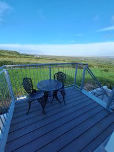 a table and two chairs on a deck with the beach at Moher Heights in Liscannor +6 photos