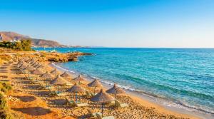 a beach with umbrellas and chairs and the ocean at Laskas Apartment in Stalís
