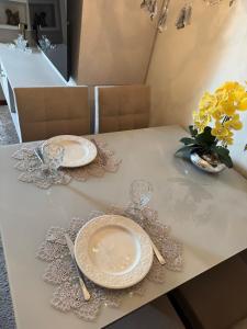 a table with plates and glasses and a vase of flowers at Apartamento Serra Espírito Santo in Serra